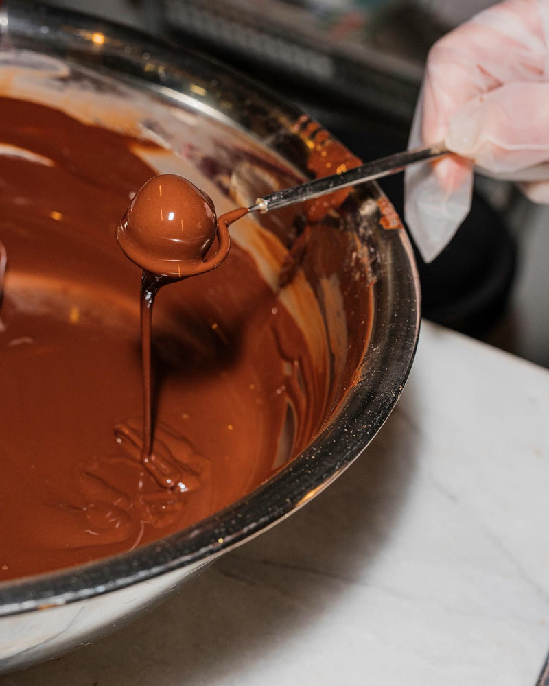 Dipping a truffle in tempered chocolate